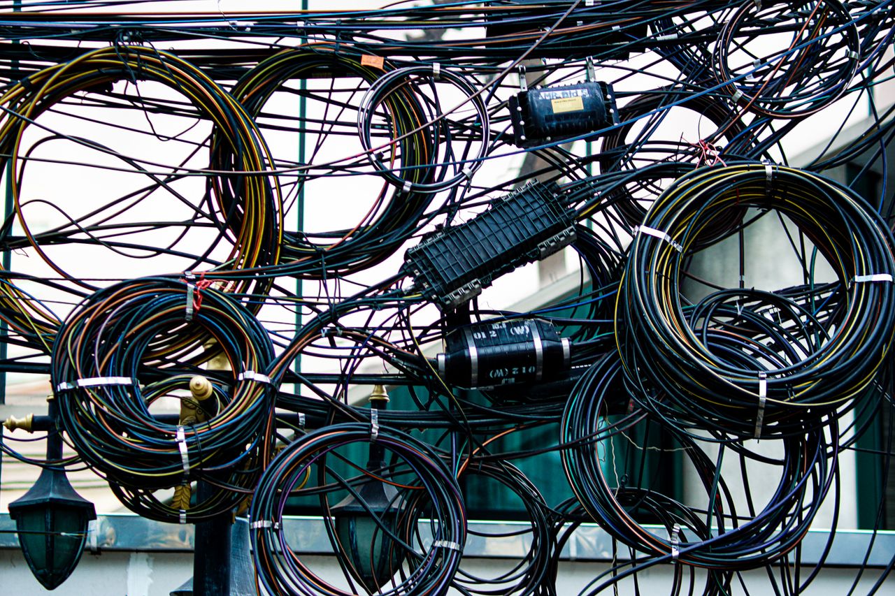 services-img Intricate network of tangled power and communication cables outdoors.