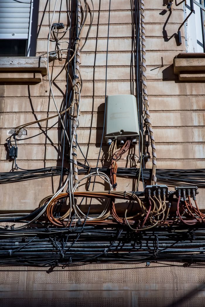 contact-img Close-up view of electrical wires and cables on a city building facade.
