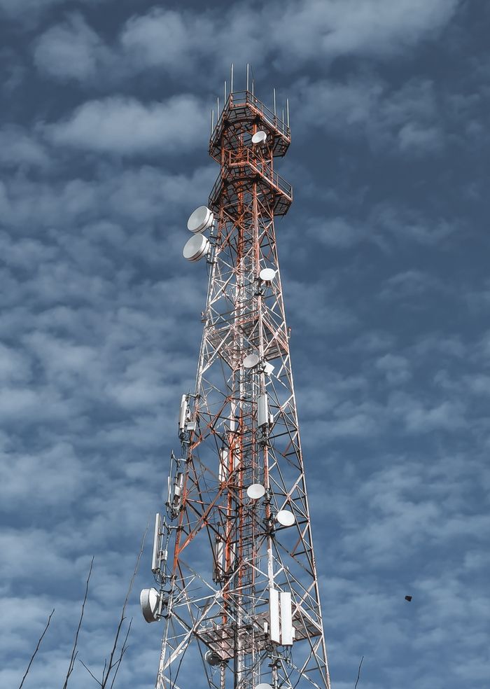 ours-journey A telecommunications tower reaching into the cloudy sky, showcasing modern technology infrastructure.