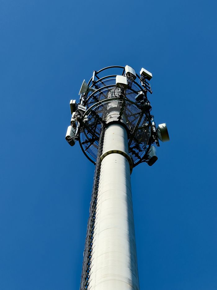 Mastering the First Impression: Your intriguing post title goes here A tall cellular tower with multiple antennas set against a bright blue sky, symbolizing communication technology.